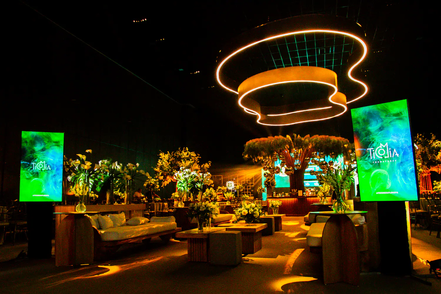 Lounge de formatura com mesas, palco e iluminação cênica.