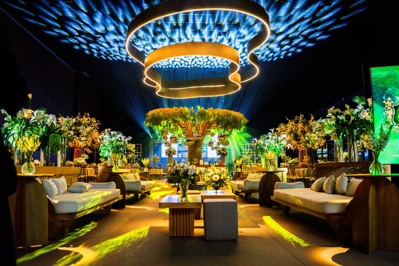 Decoração de formatura dourada com lounge e árvores iluminadas.