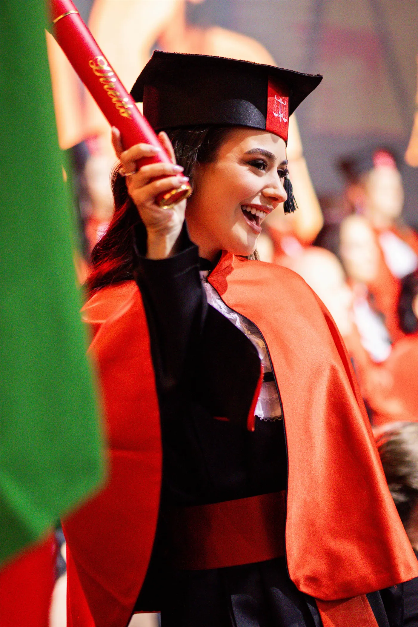 Formanda de beca vermelha celebrando durante a cerimônia de colação de grau.