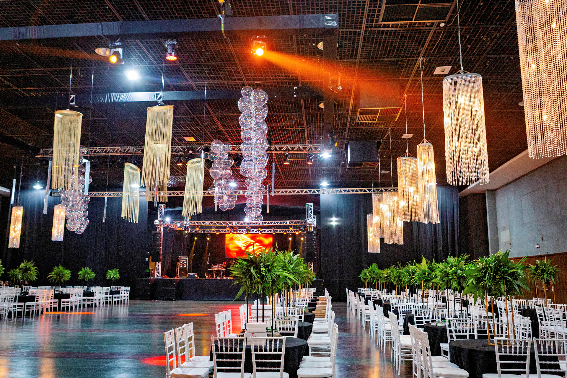 Salão de formatura montado com cadeiras, palco e iluminação cênica.