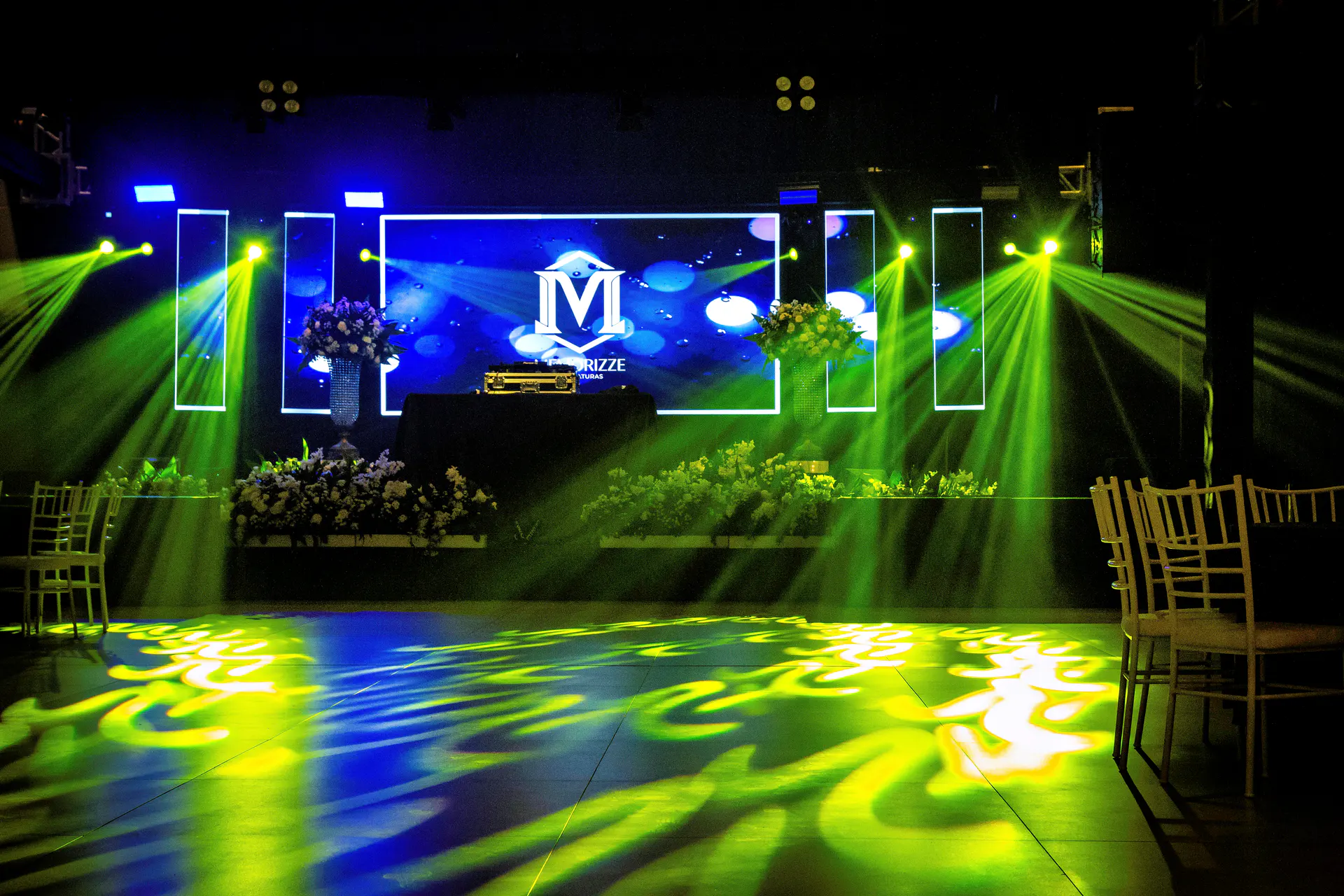 Pista de festa de formatura iluminada com palco, luzes e decoração.